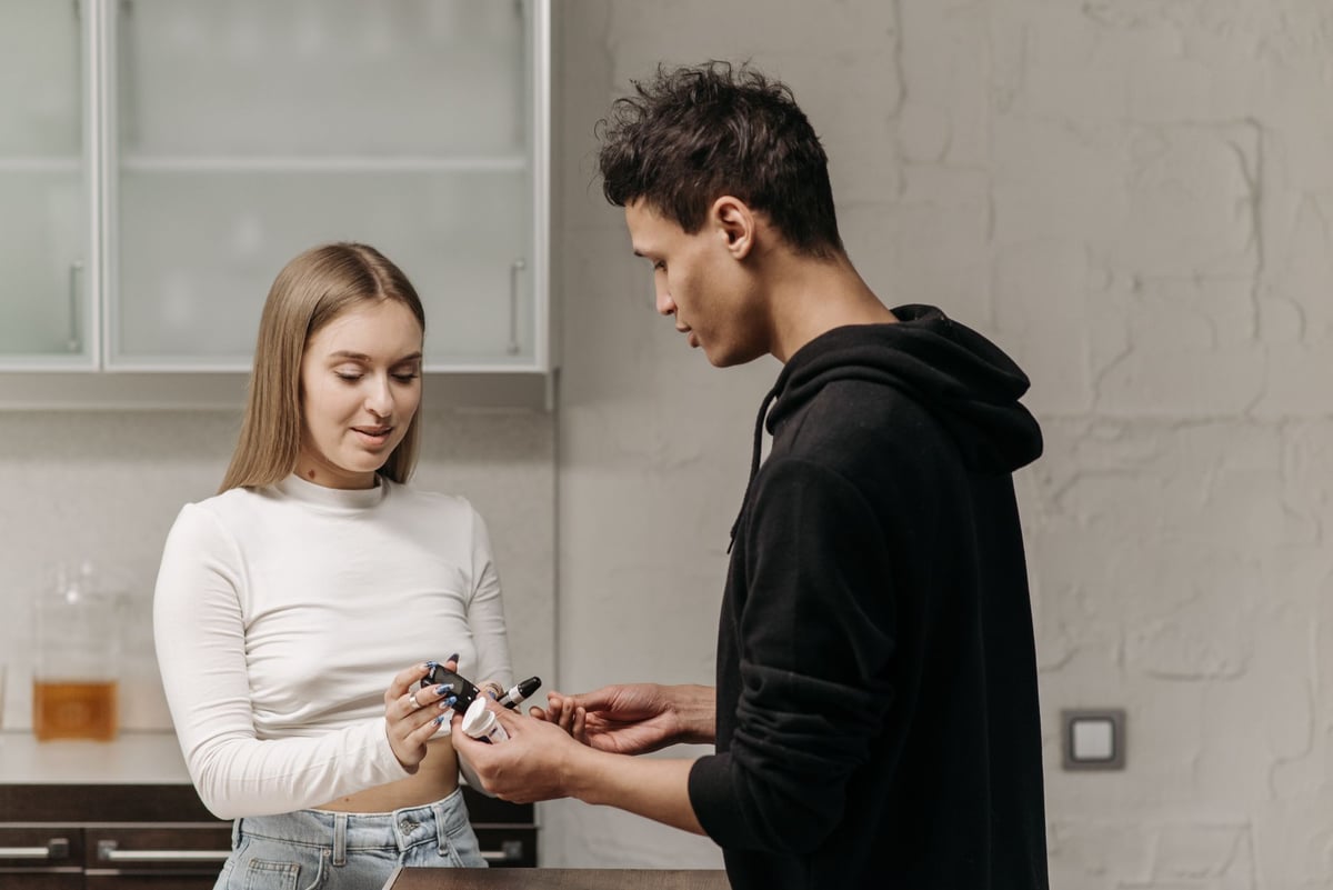 A young couple checking blood sugar levels using a glucometer indoors for diabetes management.